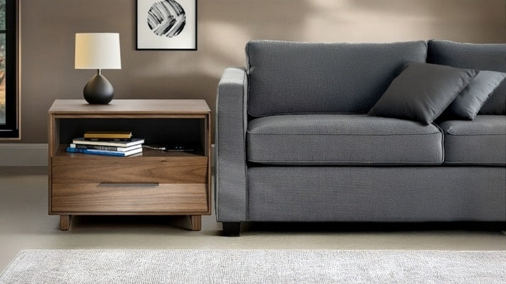 28 KAVA nightstand in walnut in decorated room next to sofa with lamp, books, and charging phone