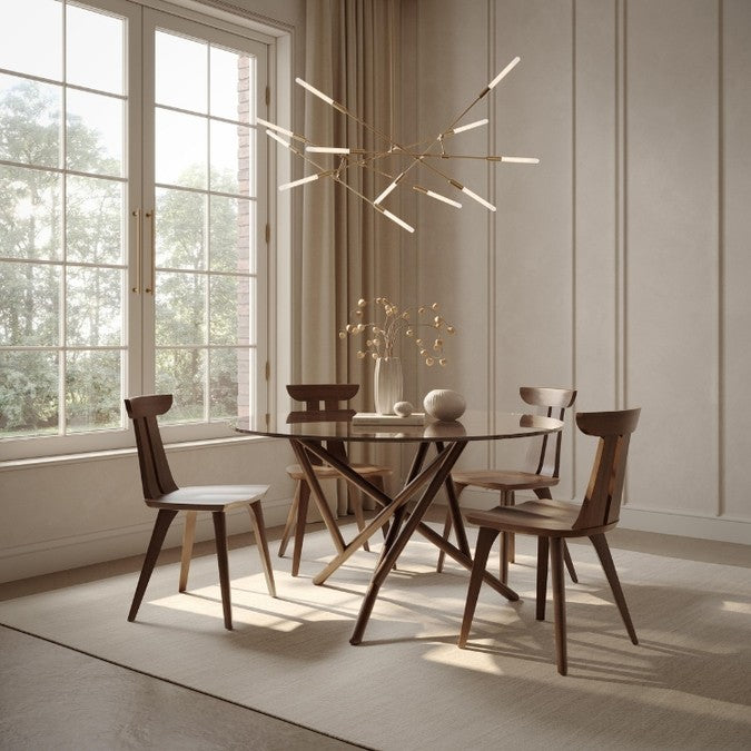 Baton Round Glass Top Table in Natural Walnut in decorated room with 4 Estelle chairs, modern light fixture, and tabletop decor