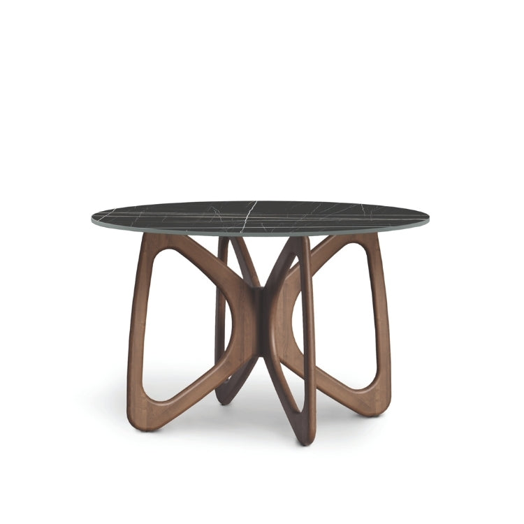 A round dining table with a dark stone top and a brown wooden sculptural base, designed in a contemporary style