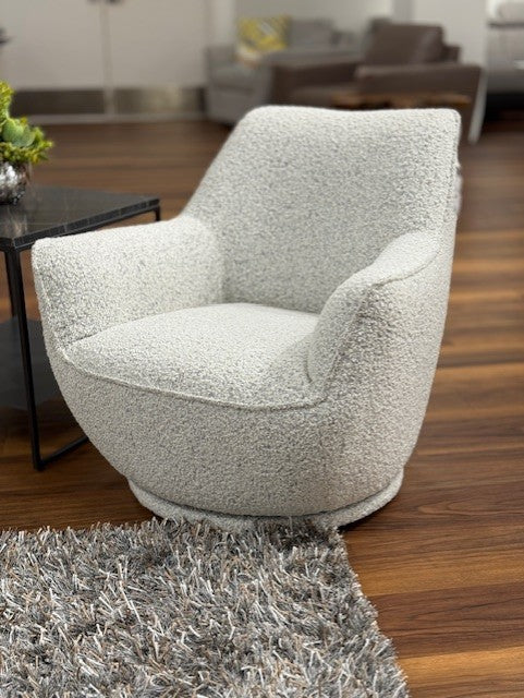 Gray textured armchair in a living room setting with a rug and table.