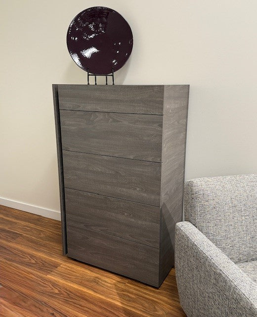 Wooden cabinet with decorative item on top next to a gray sofa in a room.
