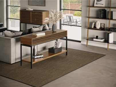Cora 1173 Console in Walnut in living room behind sofa with rug and shelving