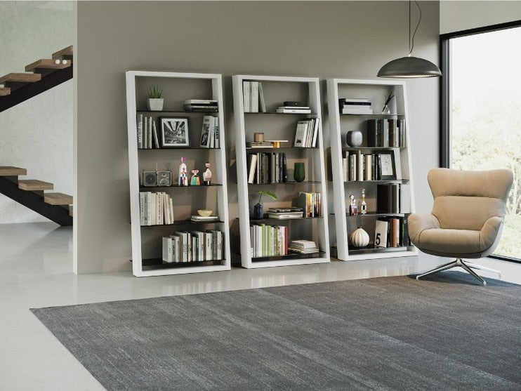 Eileen 5166 Leaning Shelf in Satin White, 3 shelving systems with books and decor, with chair and rug.