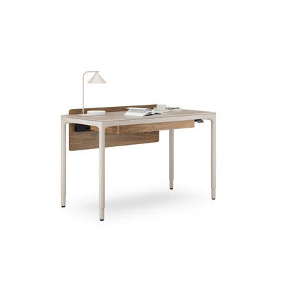 Luma Small Sit/Stand Desk in Dune with Walnut modesty panel, lamp, and books.