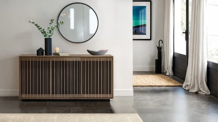 Modern interior with a wooden sideboard, round mirror, and decorative items.
