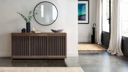 Modern interior with a wooden sideboard, round mirror, and decorative items.