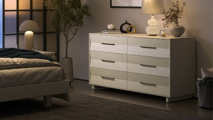 KAVA 6 drawer dresser in washed oak in decorated room with lamp, plant, vases, and books, near bed and nightstand