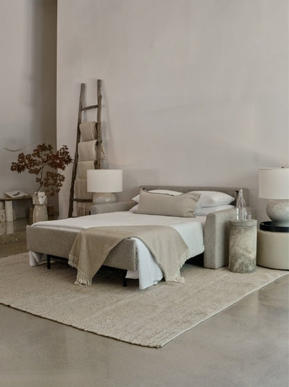 Neatly made bed in a minimalistic bedroom with neutral tones.
