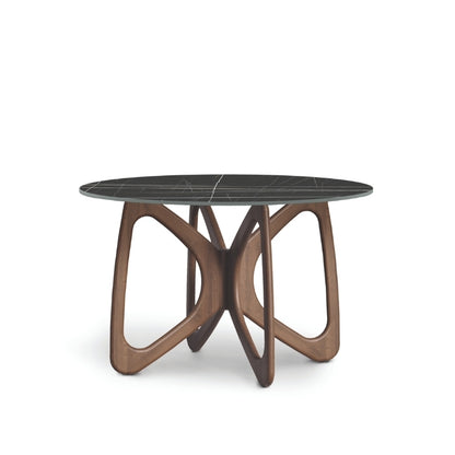 A round dining table with a dark stone top and a brown wooden sculptural base, designed in a contemporary style