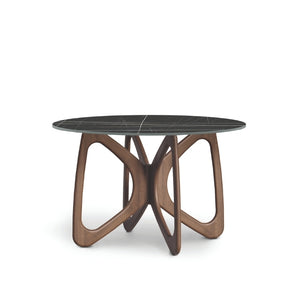A round dining table with a dark stone top and a brown wooden sculptural base, designed in a contemporary style