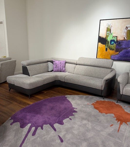 Gray sectional sofa with purple and orange abstract rug in a living room setting.