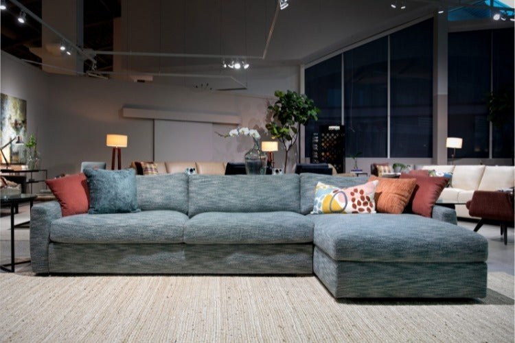 Gray sectional sofa with colorful pillows in a modern living room setting.