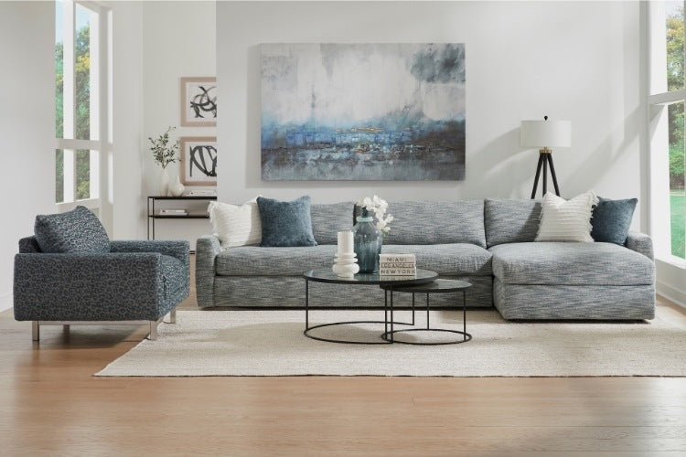 Modern living room with gray sectional sofa, armchair, and abstract artwork on the wall.