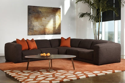 Modern living room with a brown sectional sofa, orange cushions, and a coffee table.
