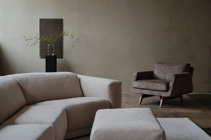 Modern living room with a beige sectional sofa and armchair against a neutral wall.