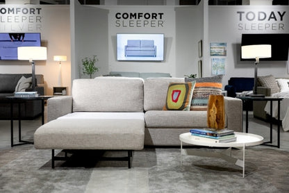 Gray sectional sofa with decorative pillows in a showroom setting, featuring 'Comfort Sleeper' branding.