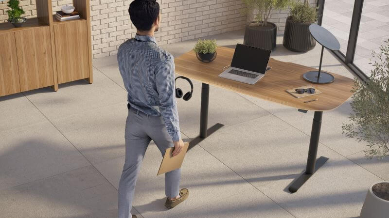 Soma 6351 Lift Desk in Natural Walnut with laptop on top and man walking towards it