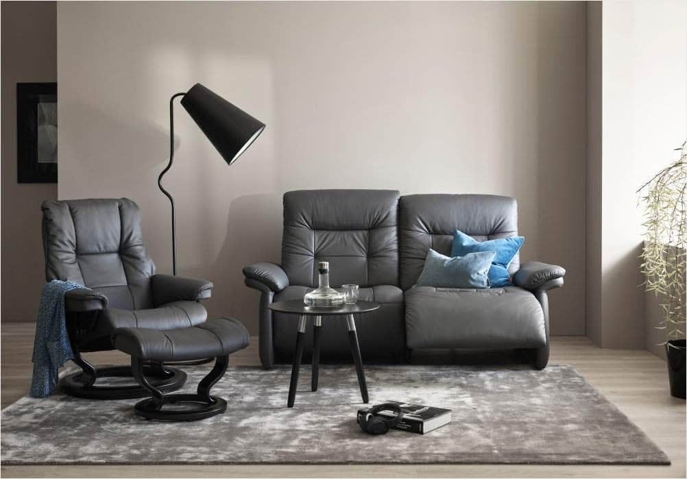 Stressless Mary sofa with Stressless Mayfair recliner pictured together in a room with a table, light and carpet 
