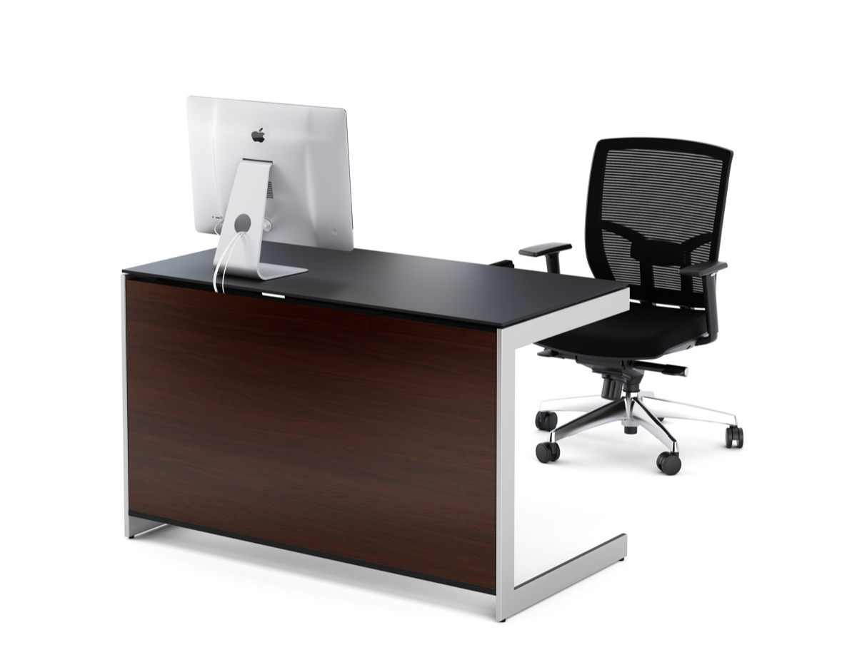 Black ergonomic office chair with mesh back behind desk with apple computer. 