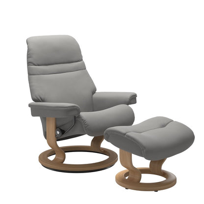 Silver grey colored sunrise recliner with matching ottoman both featuring a circular base in oak wood.