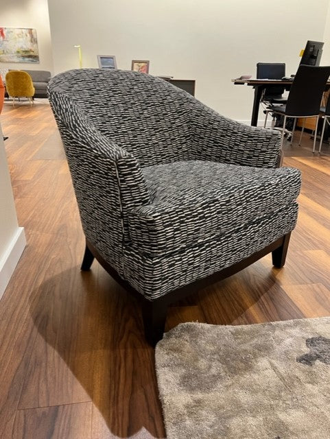 A gray upholstered Susanna chair with London zinc fabric, featuring a hard backrest and seat, positioned in an showcase setting. 