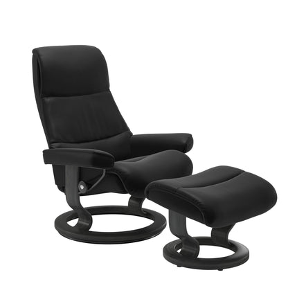 Recliner with matching ottoman in black with classic round wooden base in grey with padded armrest. 